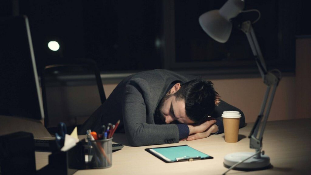 A man sleeping on his table looking overworked.