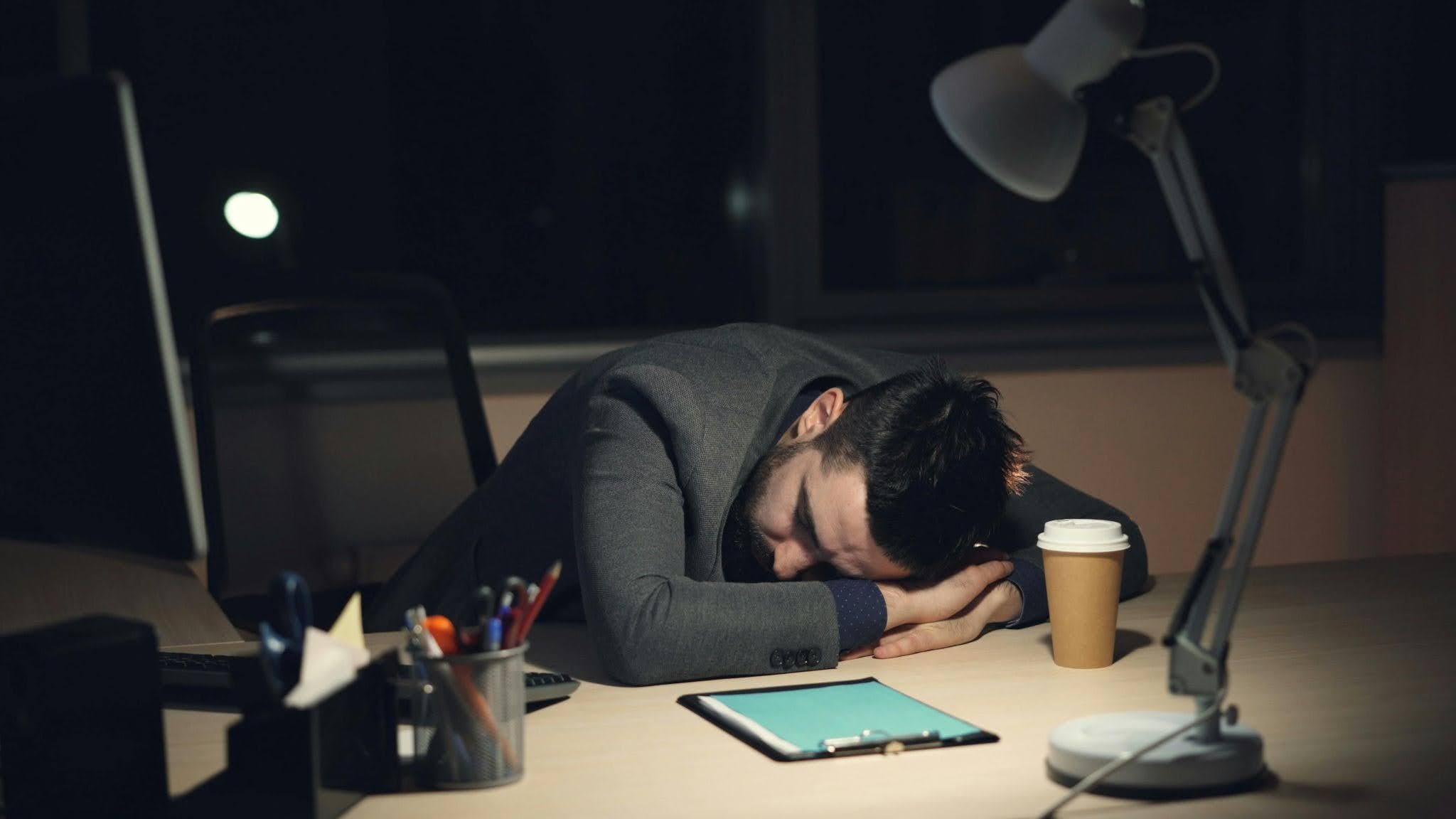 A man sleeping on his table looking overworked.