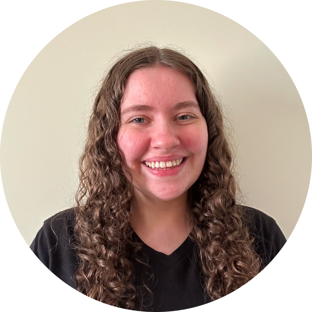 Smiling woman with long curly brown hair in a black shirt, neutral beige circular background.
