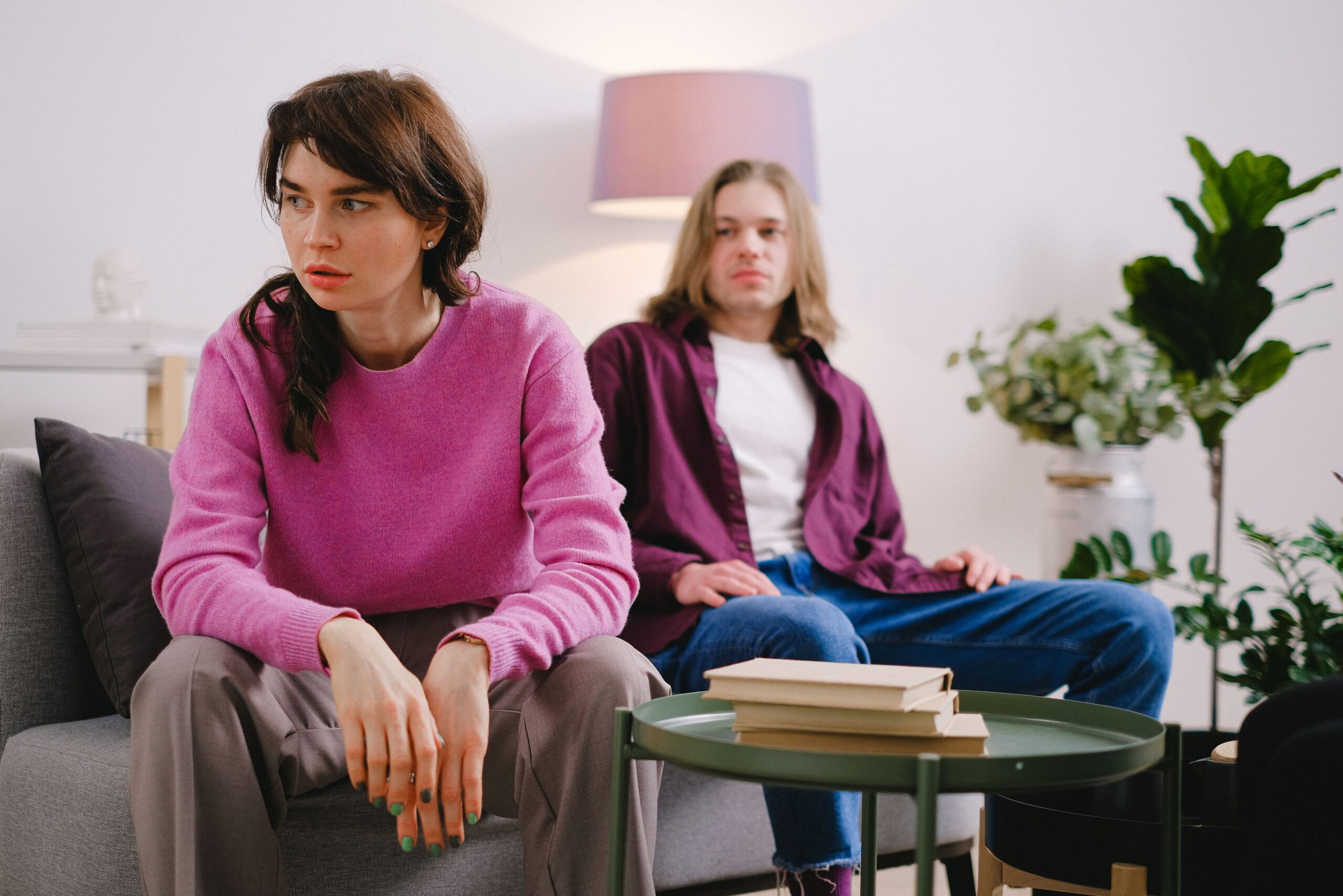 Two people sitting in a counselling setting, with a woman in the foreground and another person seated behind her in a welcoming therapy room.
